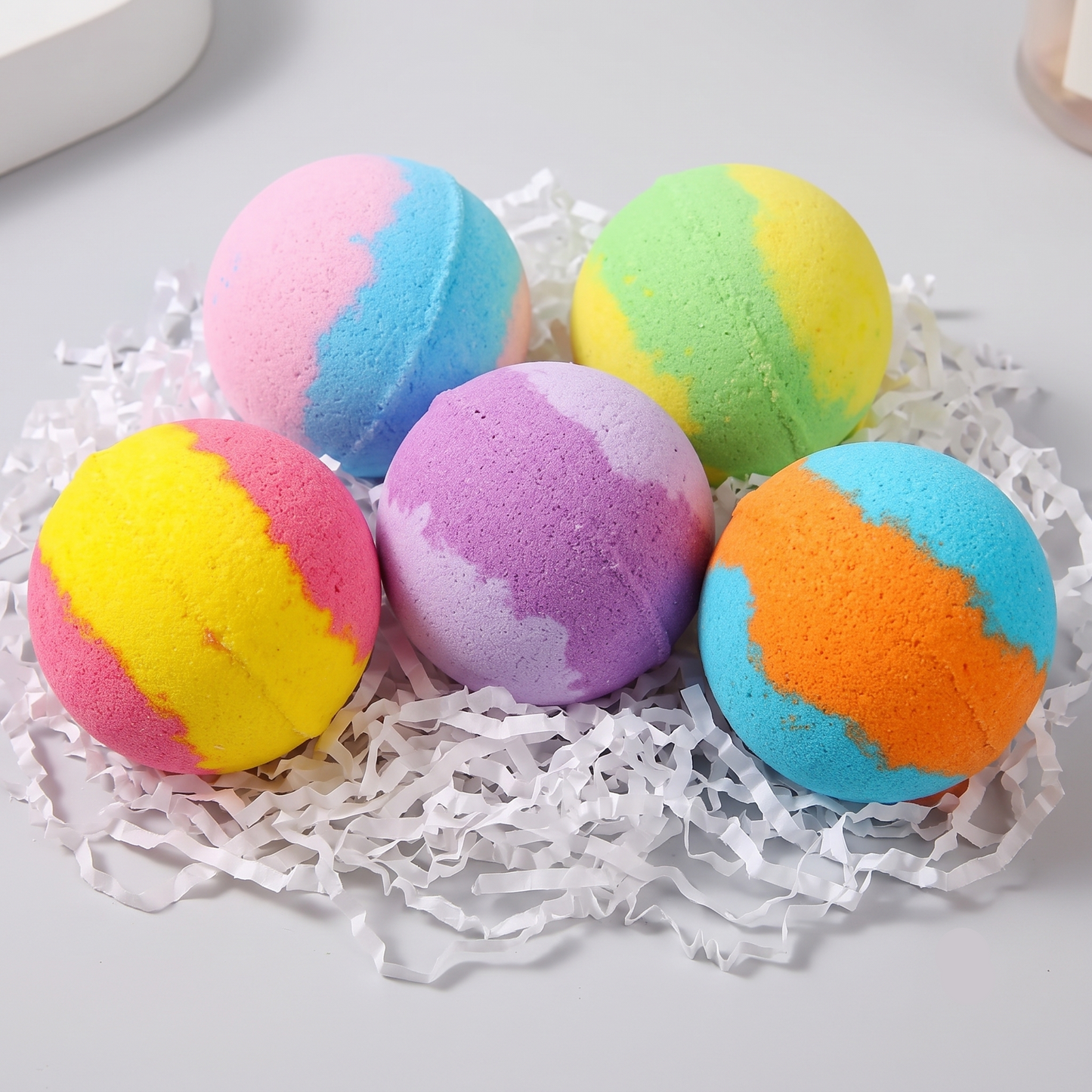 Colorful bath bombs on a white surface with shredded paper